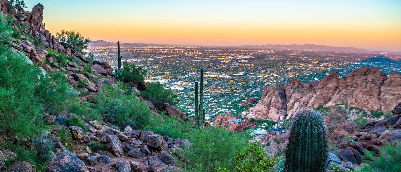 This photograph captures the sweeping views from Camelback Mountain in Phoenix, Arizona, with the city skyline stretching out below at sunset. The mountain, located at the border of Phoenix and Scottsdale, is one of the most recognizable landmarks in the region and a popular destination for hikers and sightseers.