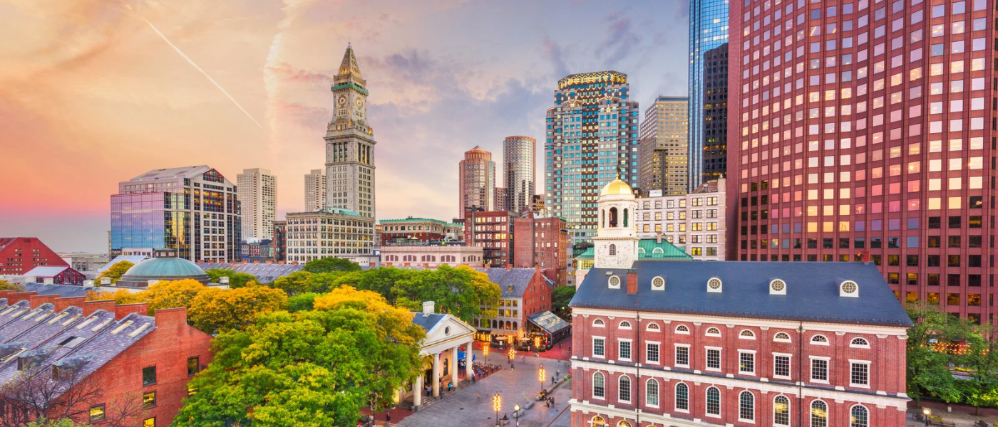 Old State House in Boston, Massachusetts, with its red brick façade and historic architecture set against the city's modern skyline at sunset.